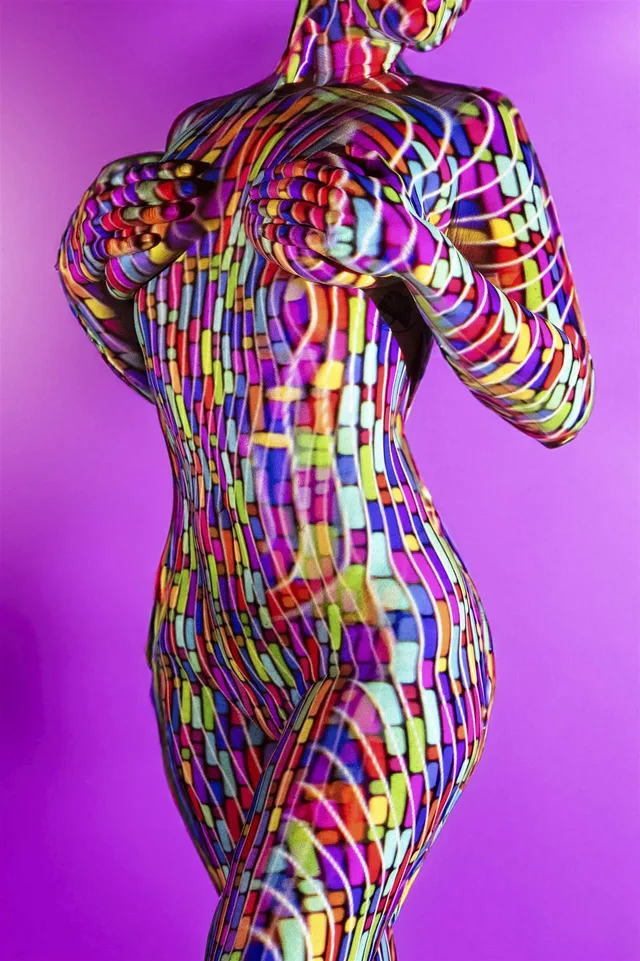 Rückenansicht mit buntem geometrischem Muster vor violettem Hintergrund.