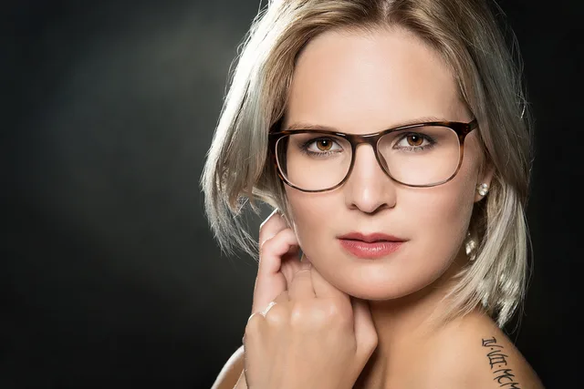 Nahes Portrait einer Frau mit Brille und direktem Blick in die Kamera.