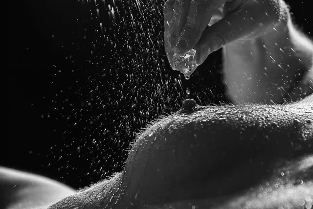 Schwarzweißes Körperdetail mit Wassertropfen und einer Hand am oberen Bildrand.