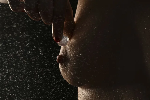 Nahaufnahme einer Hand an einem Körper mit feinen Wassertropfen.